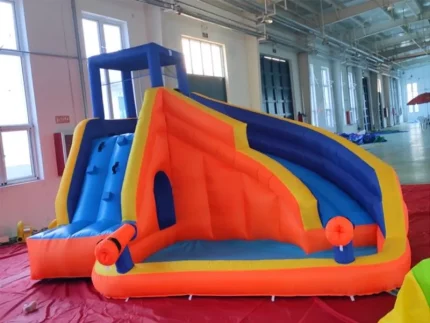 Bright orange, yellow, and blue inflatable bounce house with slide, climbing wall, and water features, perfect for kids' events. Buy online now!